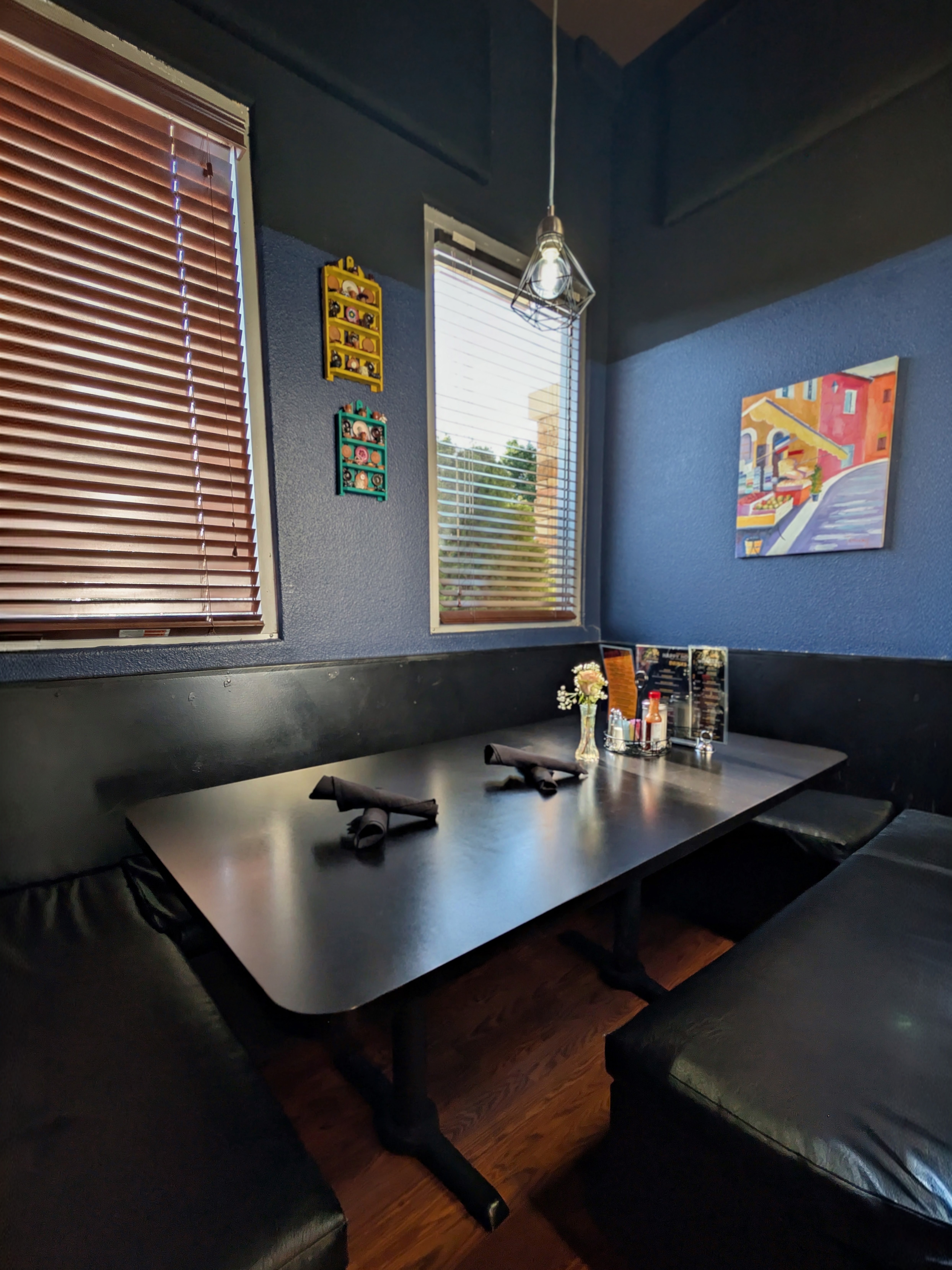 A dining booth with blue walls, framed artwork, and a set table.